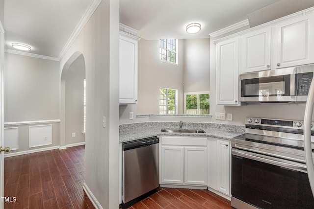 2409 Valley Haven Dr, Raleigh, NC 27603 - kitchen featuring appliances with stainless steel finishes, dark wood-style floors, white cabinetry, arched walkways, and ornamental molding