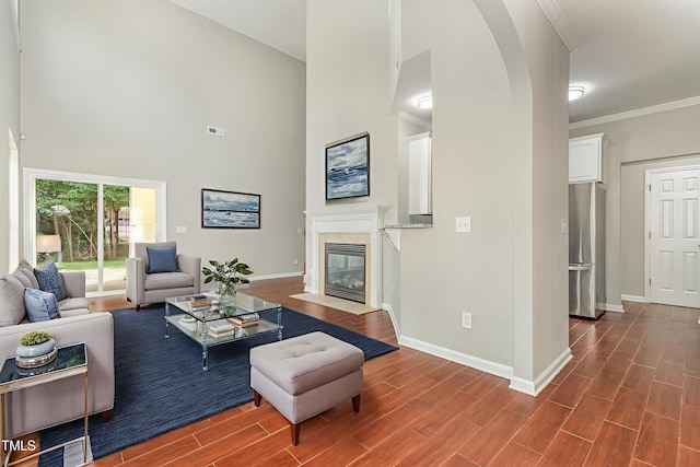 2409 Valley Haven Dr, Raleigh, NC 27603 - living area featuring a fireplace with flush hearth, a high ceiling, wood finished floors, ornamental molding, and arched walkways