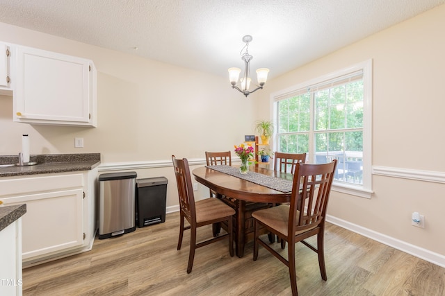 358 Tillamook Dr, Wake Forest, NC 27587 - dining room featuring light wood-style flooring, a chandelier, a textured ceiling, and baseboards