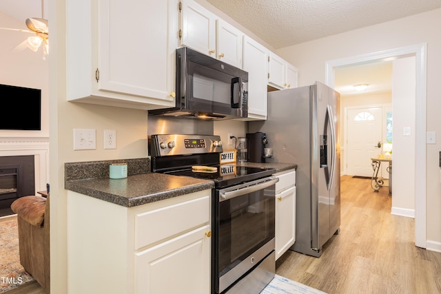 358 Tillamook Dr, Wake Forest, NC 27587 - kitchen featuring stainless steel electric range oven, black microwave, light wood-type flooring, dark countertops, and white cabinets