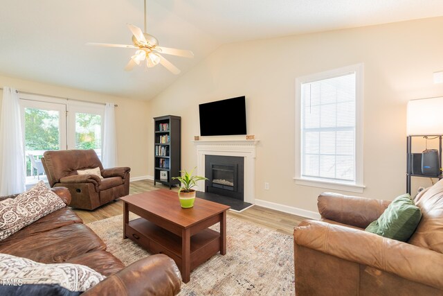 358 Tillamook Dr, Wake Forest, NC 27587 - living room featuring lofted ceiling, light wood-type flooring, baseboards, a ceiling fan, and a fireplace with flush hearth