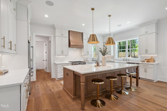 217 Dublin Rd, Raleigh, NC 27609 - kitchen featuring custom exhaust hood, light wood-style flooring, a breakfast bar area, white cabinets, and recessed lighting