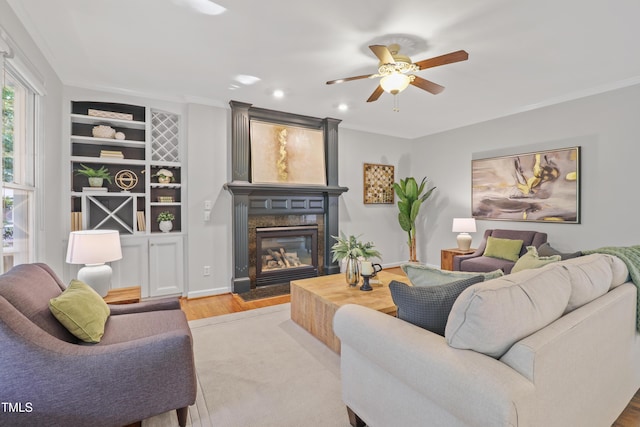 314 Chanticlair Dr, Apex, NC 27502 - living room featuring wood finished floors, a ceiling fan, a glass covered fireplace, crown molding, and built in shelves