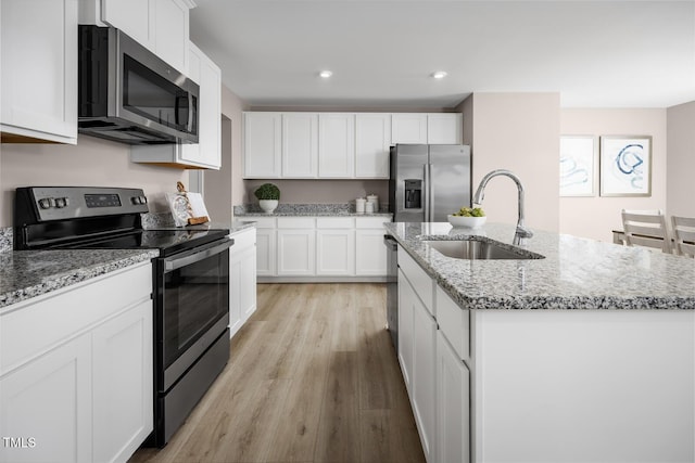 616 Impala, Wendell, NC 27591 - kitchen featuring appliances with stainless steel finishes, a sink, a kitchen island with sink, light wood-type flooring, and white cabinets