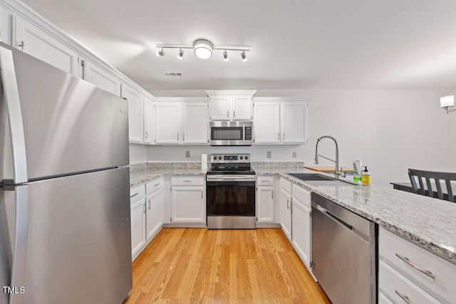 72 Justin Ct, Durham, NC 27705 - kitchen featuring stainless steel appliances, a sink, white cabinetry, light wood-type flooring, and light stone counters
