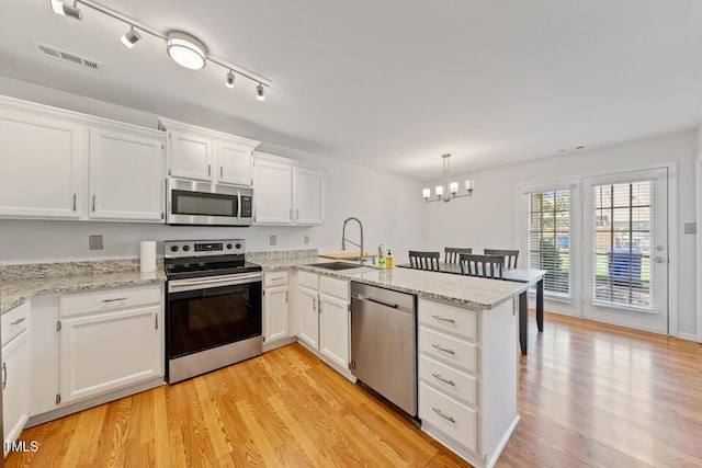 72 Justin Ct, Durham, NC 27705 - kitchen with stainless steel appliances, a sink, a peninsula, white cabinets, and a chandelier