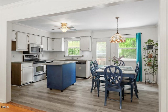 105 Otter Dr, Cary, NC 27513 - kitchen with stainless steel appliances, a kitchen island, light wood finished floors, ornamental molding, and white cabinetry