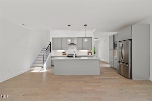 2225 Millbank Village Ct Unit 101, Raleigh, NC 27610 - kitchen with freestanding refrigerator, gray cabinets, light countertops, wall chimney range hood, and light wood-style flooring