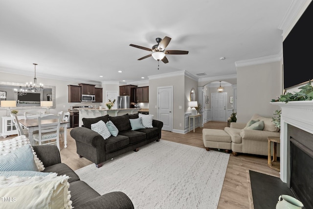 205 Willow Weald Ct, Fuquay Varina, NC 27526 - living area featuring arched walkways, a ceiling fan, a chandelier, light wood-style floors, and ornamental molding
