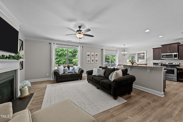205 Willow Weald Ct, Fuquay Varina, NC 27526 - living area featuring a fireplace, crown molding, a chandelier, a ceiling fan, and light wood-style flooring