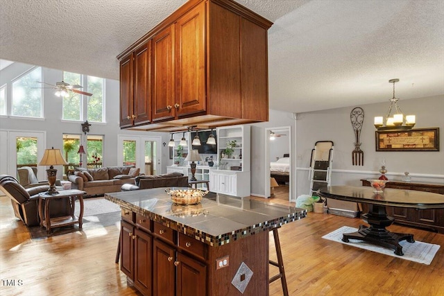 3298 Oakridge Dr Unit A, Graham, NC 27253 - kitchen with a textured ceiling, ceiling fan, light wood-style flooring, a breakfast bar area, and dark countertops