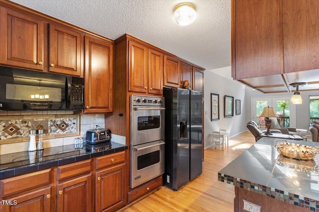 3298 Oakridge Dr Unit A, Graham, NC 27253 - kitchen with black appliances, brown cabinets, light wood finished floors, decorative backsplash, and a textured ceiling