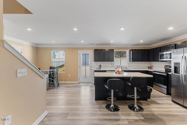 1004 Bridgewater Dr, Durham, NC 27704 - kitchen featuring stainless steel appliances, dark cabinets, light countertops, crown molding, and a center island