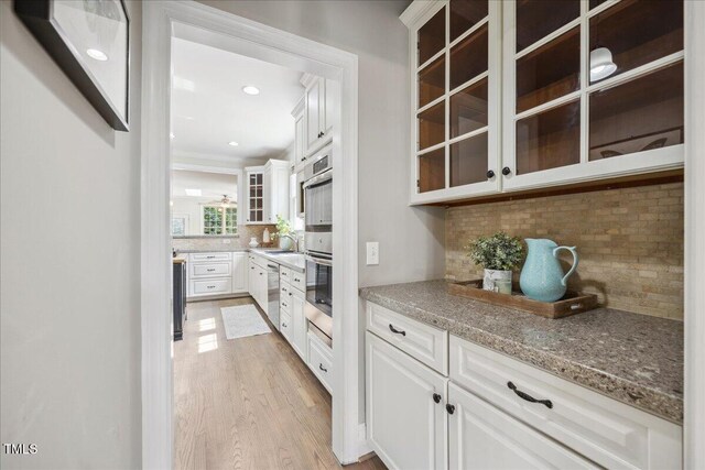 2725 Rosedale Ave, Raleigh, NC 27607 - kitchen featuring backsplash, stainless steel appliances, light wood-type flooring, white cabinetry, and glass insert cabinets