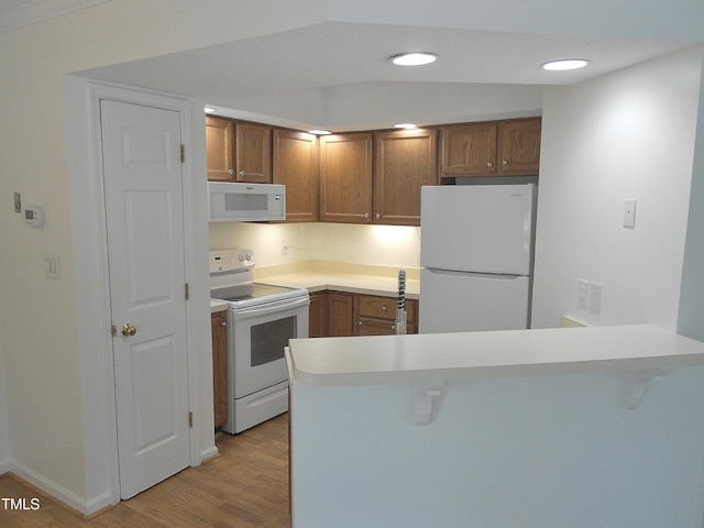 1402 Barton Place Dr, Raleigh, NC 27608 - kitchen featuring white appliances, a peninsula, brown cabinetry, a kitchen bar, and recessed lighting