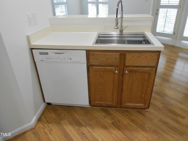 1402 Barton Place Dr, Raleigh, NC 27608 - kitchen with white dishwasher, a sink, wood finished floors, brown cabinetry, and light countertops