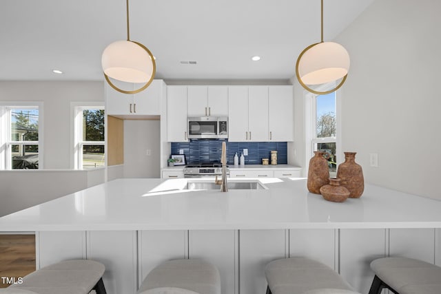 517 Coleman St, Raleigh, NC 27610 - kitchen with appliances with stainless steel finishes, white cabinets, a breakfast bar, backsplash, and light countertops