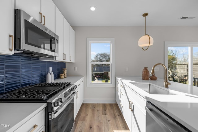 517 Coleman St, Raleigh, NC 27610 - kitchen with stainless steel appliances, a sink, light wood-style floors, tasteful backsplash, and light countertops