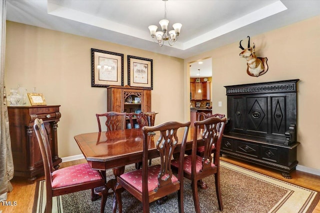 1304 Double Oak Ln, Willow Springs, NC 27592 - dining room with a chandelier, light wood finished floors, a raised ceiling, and baseboards