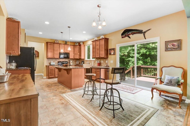 1304 Double Oak Ln, Willow Springs, NC 27592 - kitchen with black appliances, a kitchen island, tasteful backsplash, a kitchen bar, and decorative light fixtures