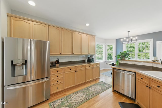 2933 Creek Moss Ave, Wake Forest, NC 27587 - kitchen with stainless steel appliances, light brown cabinetry, light wood-type flooring, a chandelier, and tasteful backsplash
