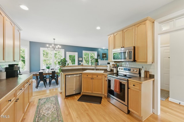 2933 Creek Moss Ave, Wake Forest, NC 27587 - kitchen featuring appliances with stainless steel finishes, light brown cabinets, a peninsula, light wood-style floors, and a chandelier