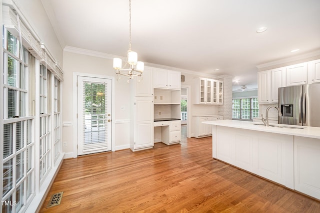 7605 Sandy Lake Ct, Raleigh, NC 27613 - kitchen featuring stainless steel fridge, white cabinets, light wood-style floors, crown molding, and light countertops