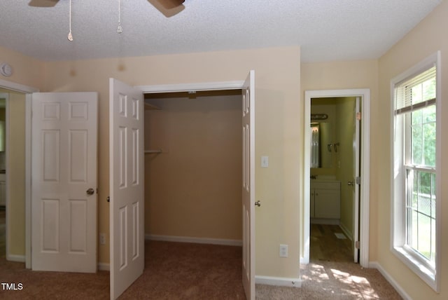 5949 Sandy Run, Knightdale, NC 27545 - unfurnished bedroom featuring multiple windows, carpet flooring, a closet, connected bathroom, and a textured ceiling