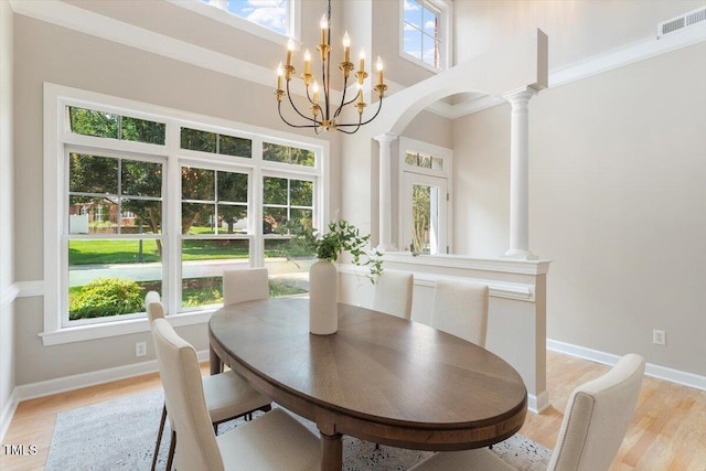 4724 Ludwell Branch Ct, Raleigh, NC 27612 - dining area featuring ornate columns, light wood-style floors, a chandelier, arched walkways, and baseboards