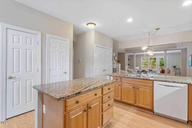 4724 Ludwell Branch Ct, Raleigh, NC 27612 - kitchen with white dishwasher, a sink, light wood-style floors, a kitchen island, and light stone countertops