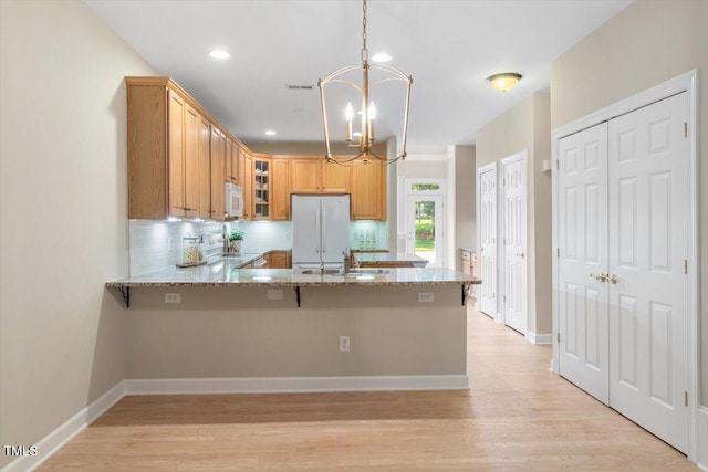 4724 Ludwell Branch Ct, Raleigh, NC 27612 - kitchen with white appliances, a chandelier, light stone countertops, a sink, and glass insert cabinets