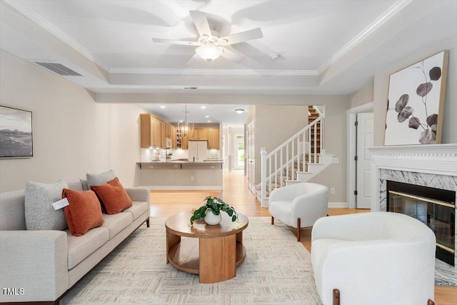 4724 Ludwell Branch Ct, Raleigh, NC 27612 - living area with stairway, light wood-style flooring, ceiling fan, a tray ceiling, and crown molding