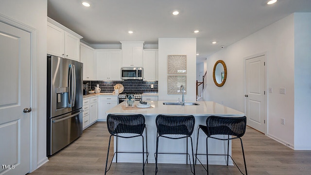 8763 Wardle Ct, Wake Forest, NC 27587 - kitchen featuring stainless steel appliances, a sink, a kitchen bar, a center island with sink, and wood finished floors
