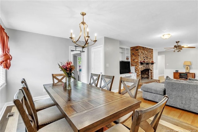239 Rainier Dr, Fayetteville, NC 28314 - dining area featuring a chandelier, light wood-style floors, a fireplace, a ceiling fan, and baseboards