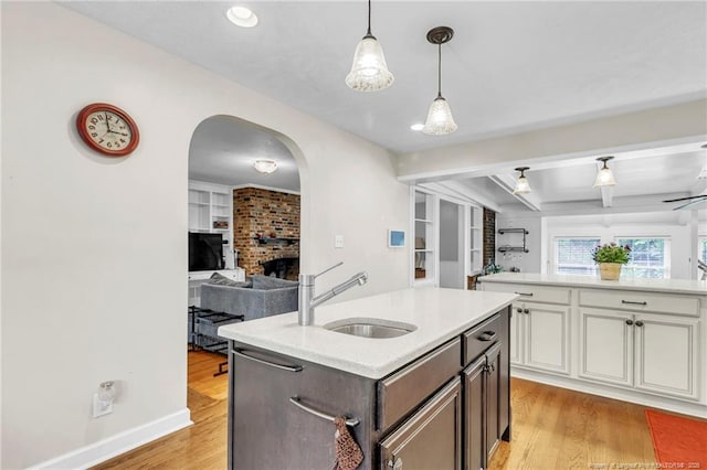 239 Rainier Dr, Fayetteville, NC 28314 - kitchen with a sink, open floor plan, light countertops, a brick fireplace, and light wood-type flooring