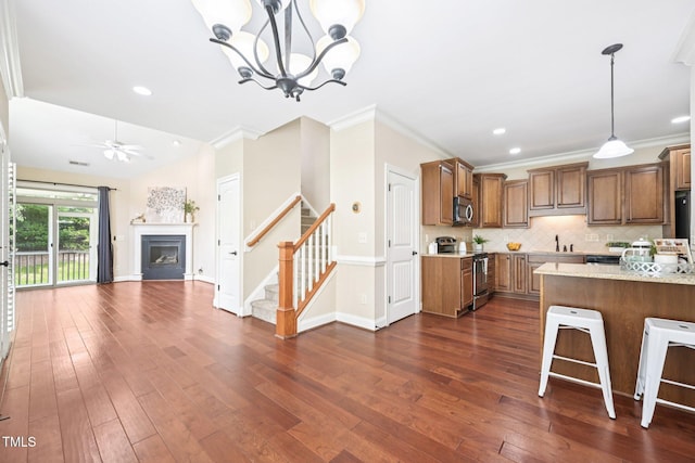 1090 Indigo Ridge Pl, Cary, NC 27519 - kitchen with stainless steel appliances, brown cabinetry, dark wood-style floors, backsplash, and a fireplace