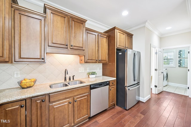 1090 Indigo Ridge Pl, Cary, NC 27519 - kitchen featuring stainless steel appliances, washer and dryer, backsplash, brown cabinetry, and dark wood finished floors