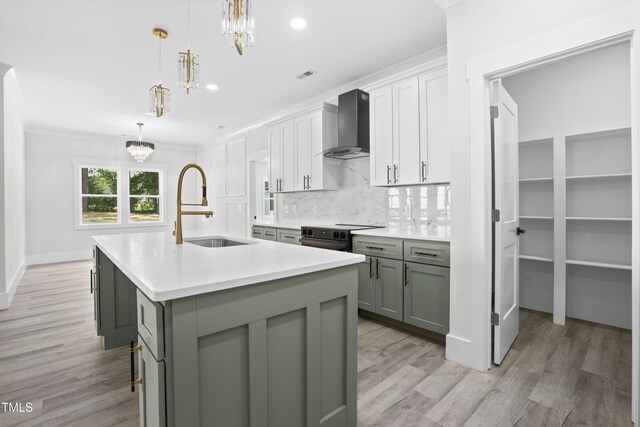 107 Mohave Dr, Louisburg, NC 27549 - kitchen with wall chimney range hood, a sink, a chandelier, light wood finished floors, and a center island with sink