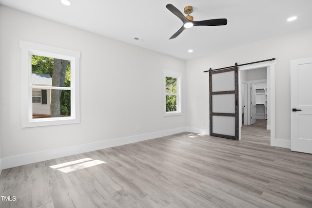 107 Mohave Dr, Louisburg, NC 27549 - unfurnished bedroom featuring a barn door, multiple windows, light wood-type flooring, baseboards, and recessed lighting