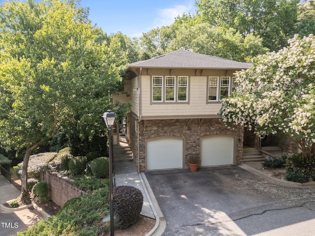 4511 Crab Creek Dr Unit 101, Raleigh, NC 27612 - view of front of house with stone siding, driveway, stairway, a garage, and roof with shingles