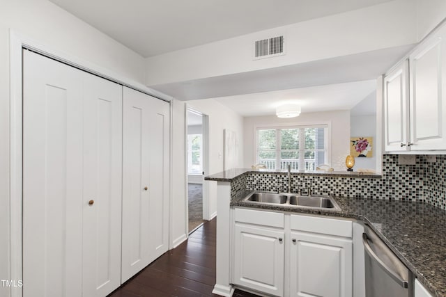 911 Washington St Unit 304, Raleigh, NC 27605 - kitchen with stainless steel dishwasher, a sink, a peninsula, white cabinets, and backsplash