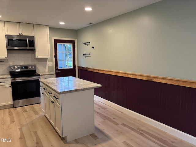 301 Roseland Ave, Durham, NC 27712 - kitchen with appliances with stainless steel finishes, light wood-style floors, a wainscoted wall, white cabinetry, and light stone countertops