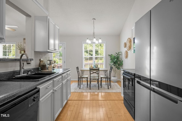 508 Hidden Cellars Dr, Holly Springs, NC 27540 - kitchen with black appliances, a chandelier, light wood-style flooring, dark countertops, and decorative light fixtures