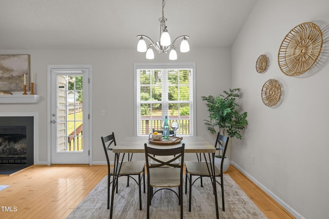508 Hidden Cellars Dr, Holly Springs, NC 27540 - dining area featuring light wood finished floors, a chandelier, and a fireplace with flush hearth