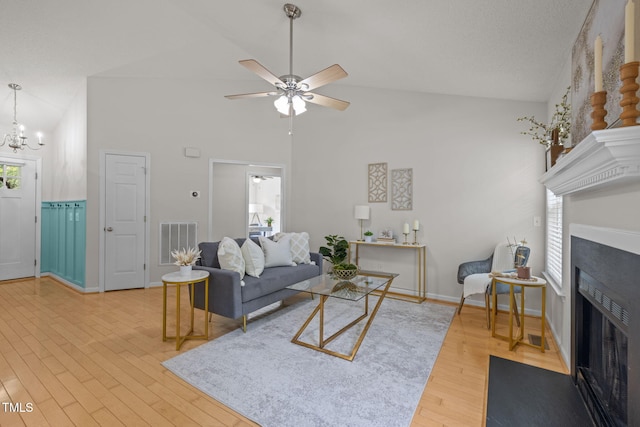 508 Hidden Cellars Dr, Holly Springs, NC 27540 - living room with a fireplace with flush hearth, wood finished floors, a ceiling fan, a chandelier, and high vaulted ceiling