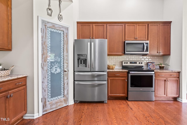 1400 Manley Ct, Fuquay Varina, NC 27526 - kitchen with appliances with stainless steel finishes, decorative backsplash, brown cabinetry, and light wood-style flooring