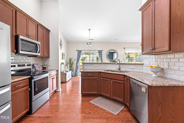1400 Manley Ct, Fuquay Varina, NC 27526 - kitchen featuring appliances with stainless steel finishes, tasteful backsplash, a peninsula, wood finished floors, and lofted ceiling
