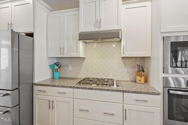 1161 Tulip Poplar Rd, Fuquay Varina, NC 27526 - kitchen featuring appliances with stainless steel finishes, under cabinet range hood, white cabinetry, decorative backsplash, and light stone countertops