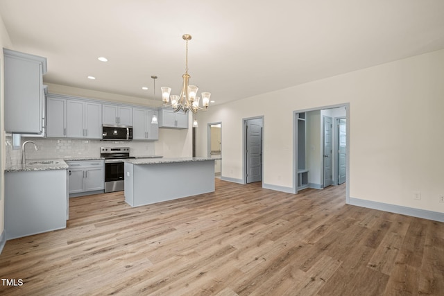 147 Harmony Trl, Broadway, NC 27505 - kitchen with appliances with stainless steel finishes, a sink, a chandelier, light wood-style floors, and a kitchen island