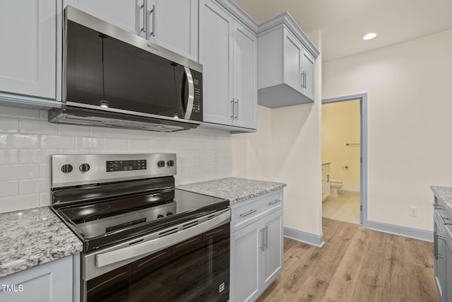 147 Harmony Trl, Broadway, NC 27505 - kitchen featuring stainless steel appliances, light wood-style flooring, light stone counters, backsplash, and recessed lighting